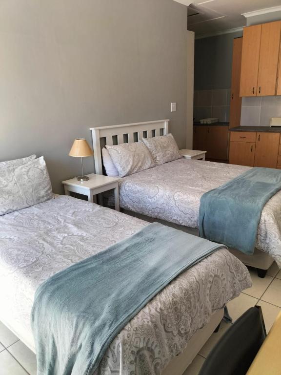 Un dormitorio con dos camas y una cocina. en Gqeberha Self Catering Apartments, en Kensington