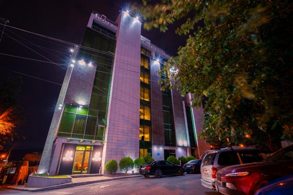 un edificio con coches aparcados delante de él por la noche en Capitol Hotel By umbrella en Tiflis