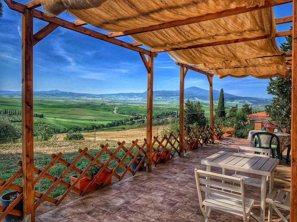a wooden pergola with chairs and tables on a patio at Agriturismo il Casato - il Torchio in Pienza