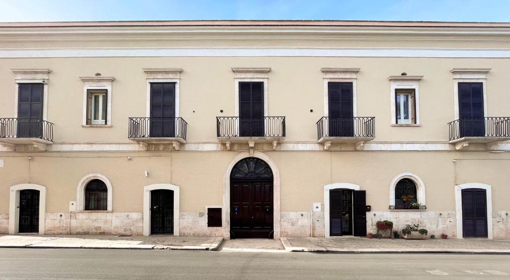 um grande edifício branco com portas e janelas pretas em B&B Palazzo 1906 - Eco dimora storica em Bitetto
