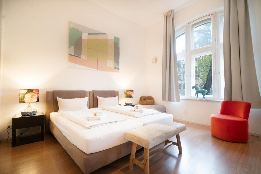 a bedroom with a large white bed and a red chair at Heger Tor Apartments in Osnabrück