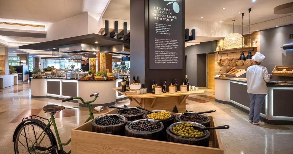 a person standing in a bakery with a table of food at Valamar Diamant Hotel in Poreč