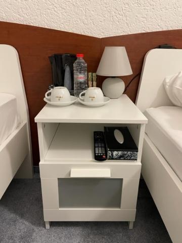 einem weißen Nachttisch mit zwei Tassen und einer Lampe in der Unterkunft Hotel Starlight in Frankfurt am Main