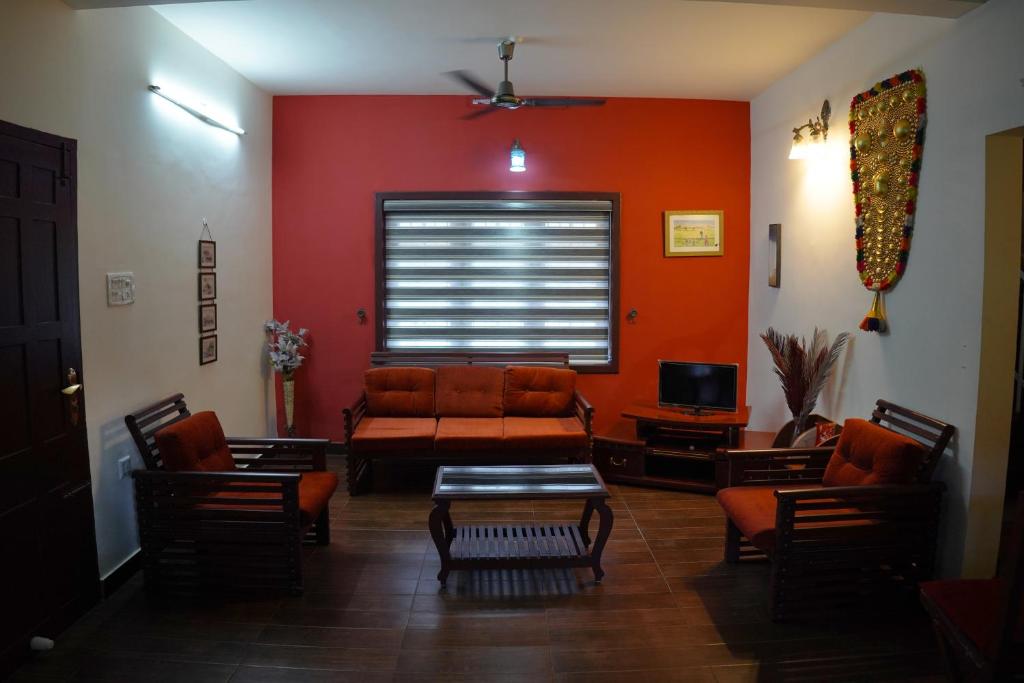 a living room with red walls and a couch and chairs at Wetzlar Villas in Angamaly