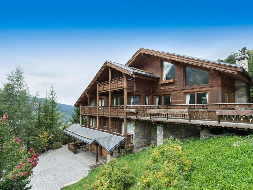 a large wooden house on top of a hill at Chalet Les Solans in Les Allues