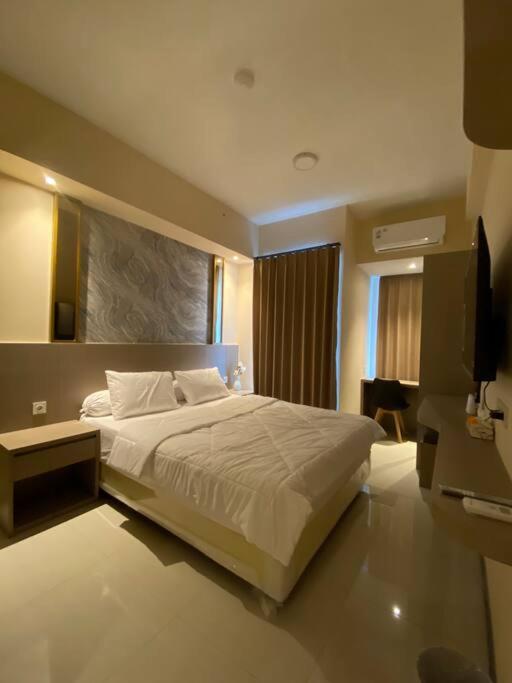 a bedroom with a large bed and a television at Luxury Studio Benson Apartment, Pakuwon Mall in Surabaya