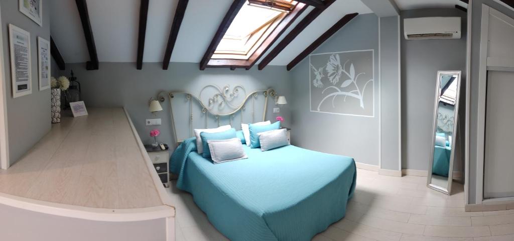 a bedroom with a blue bed and a skylight at Hospedaje San Francisco in Segovia