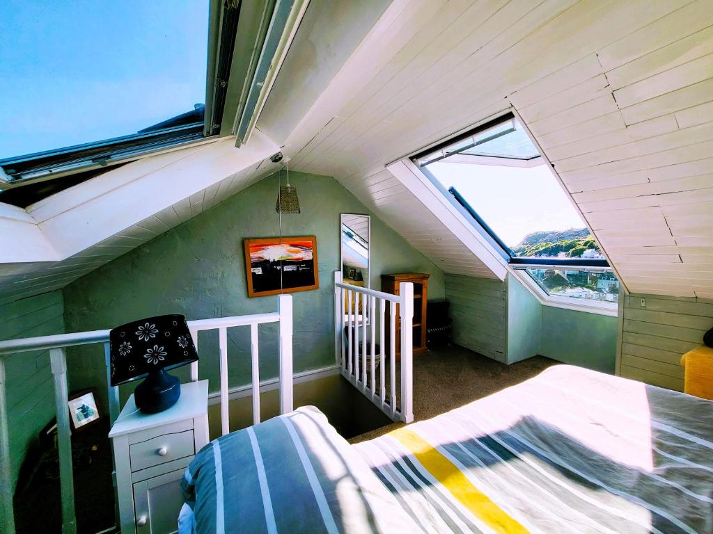 a attic room with a bed and two windows at Tackleway privileged Sea Views Hastings old town whole house 3 beds in Hastings