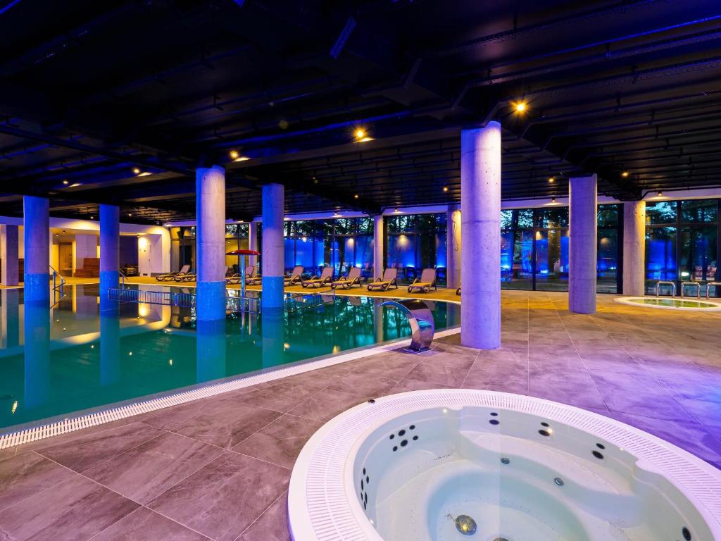 a swimming pool with blue columns in a building at Resort Król Plaza Spa & Wellness in Jarosławiec