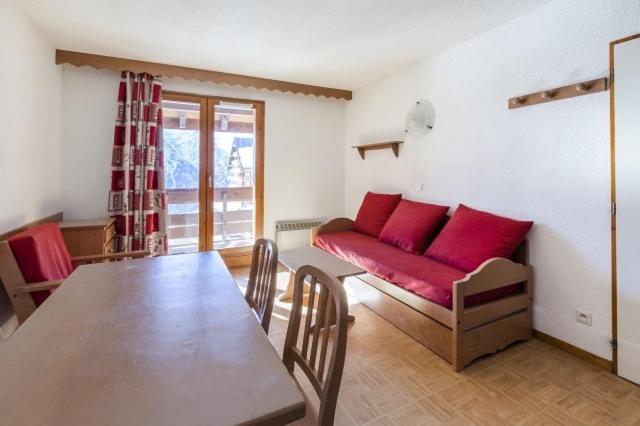 a living room with a table and a red couch at Appartement 4p - Parking Privé in Les Deux Alpes