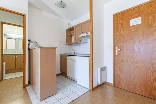 a kitchen with white appliances and a wooden door at Appartement 4p - Parking Privé in Les Deux Alpes