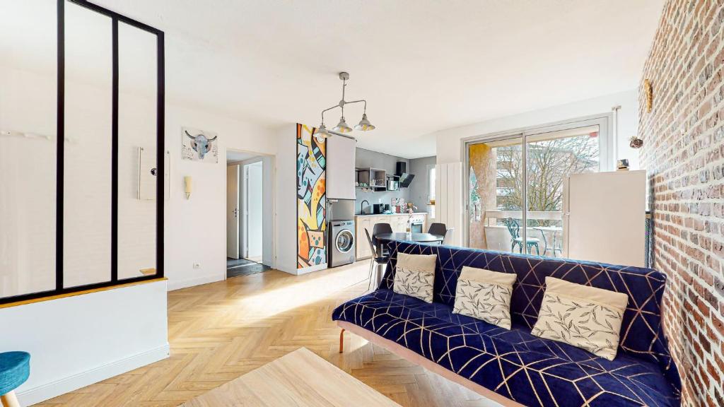 a living room with a blue couch and a brick wall at HIPPODROME - Piscine - Parking Free - Métro in Toulouse