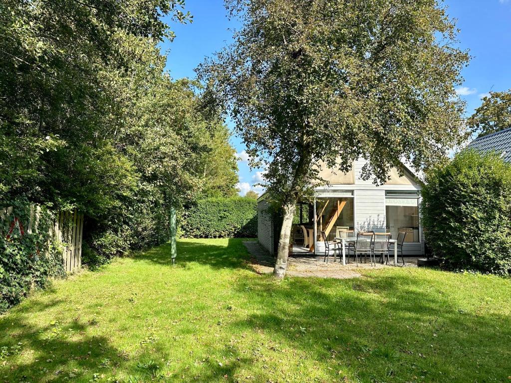 een huis met een tuin met een tafel en stoelen bij Noordzeehuisje in Sint Maartensvlotbrug