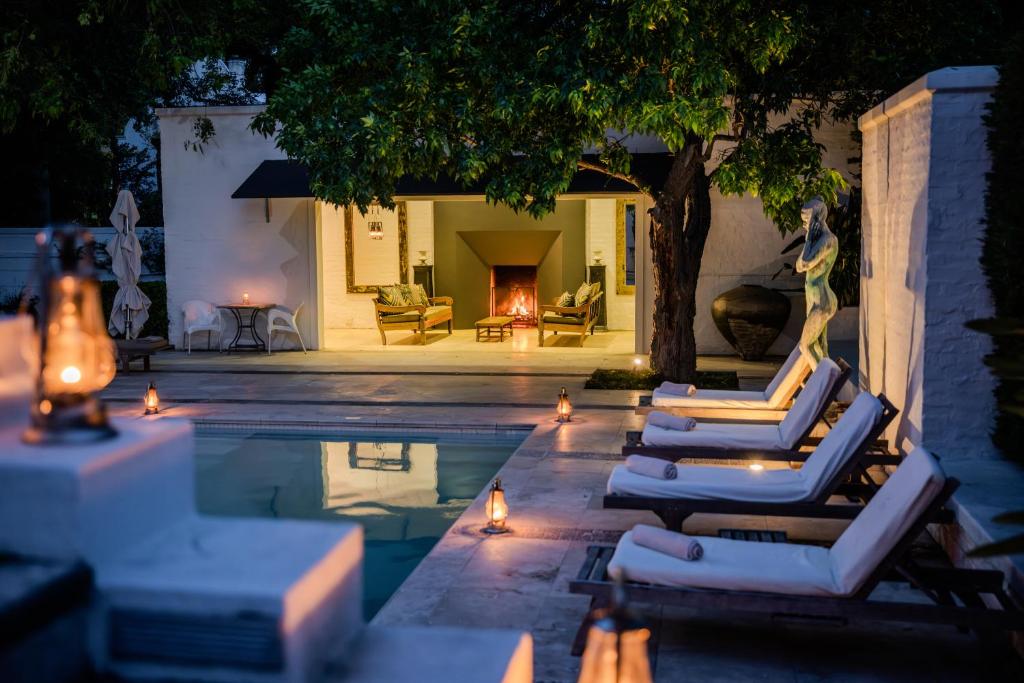 a swimming pool with lounge chairs and a fireplace at Grande Provence in Franschhoek