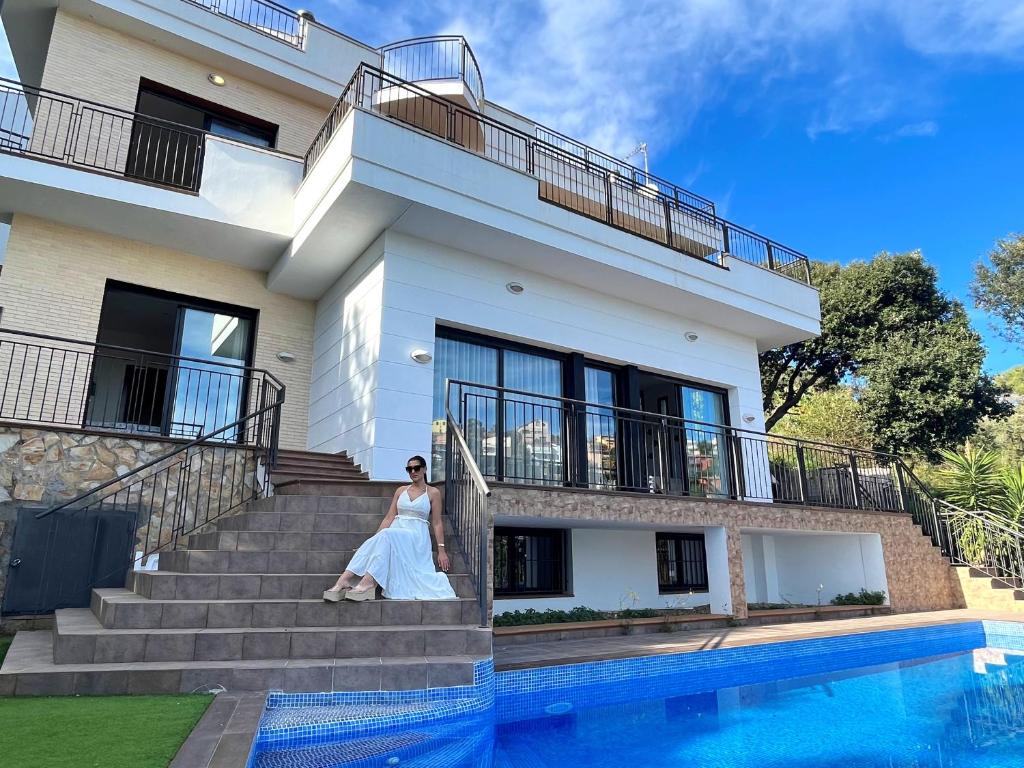 una mujer está parada en los escalones de una casa en Villa de lujo con vistas al mar y piscina privada, en Santa Susanna