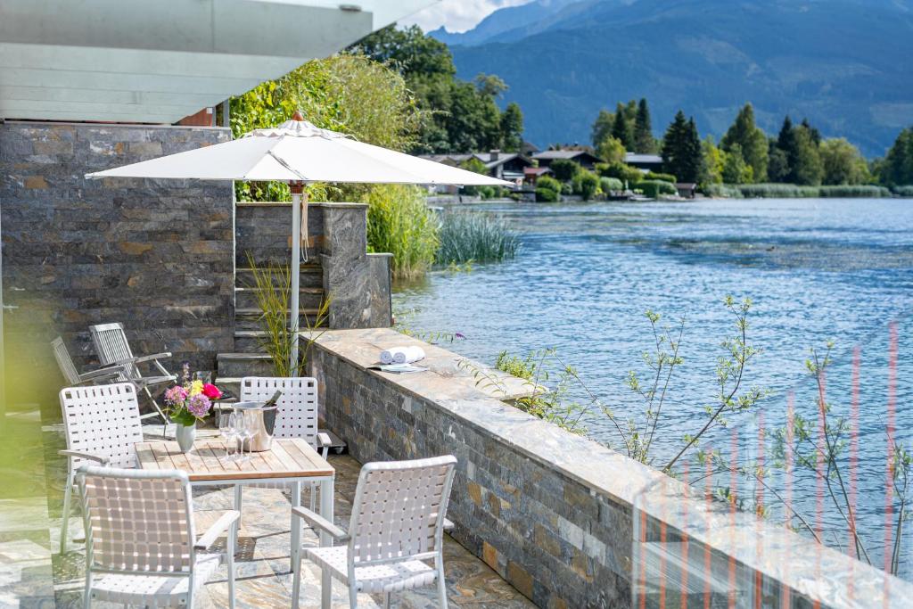 a table and chairs with an umbrella next to a river at Lakefront Suite 148 by we rent in Zell am See