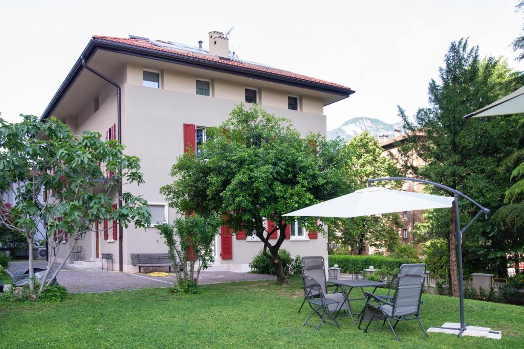 a table with chairs and an umbrella in a yard at B&B PIEDICASTELLO in Trento