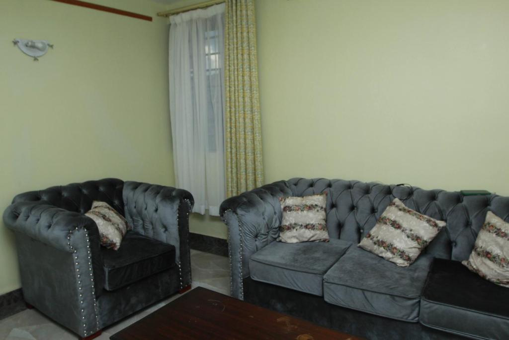 un soggiorno con due divani in pelle e una sedia di Cherry home a Nairobi