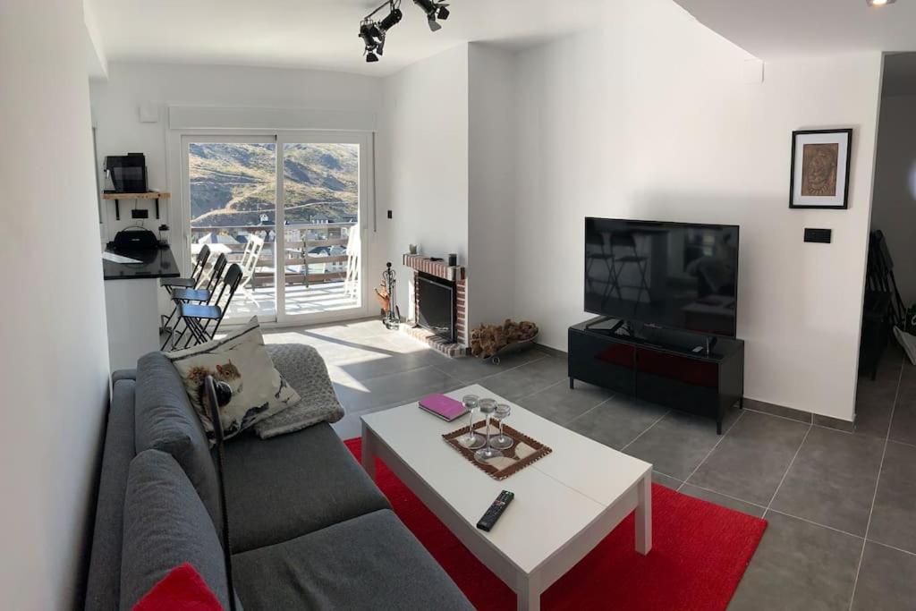 a living room with a couch and a tv at APARTAMENTO PRECIOSO SOL Y SIERRA in Sierra Nevada