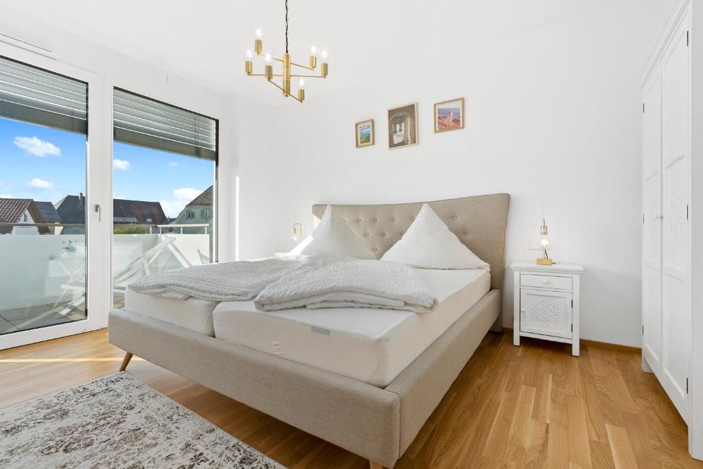 a white bedroom with a bed and a window at ANYTIME - Riedlepark Apartments in Friedrichshafen