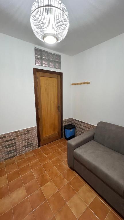 salon z kanapą i drewnianymi drzwiami w obiekcie STANZA CORSICA w mieście Alghero