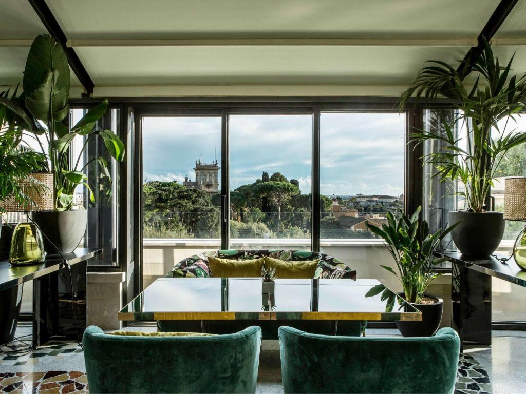 sala de estar con mesa, sillas y ventana grande en Sofitel Roma Villa Borghese, en Roma