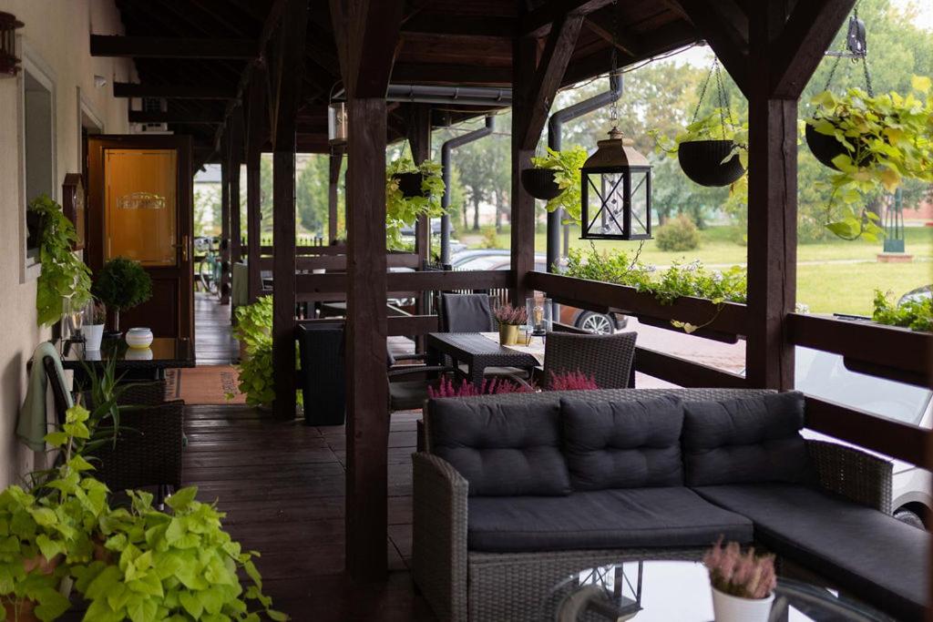 un porche con sofá, mesas y plantas en Kanclerz, en Zamość