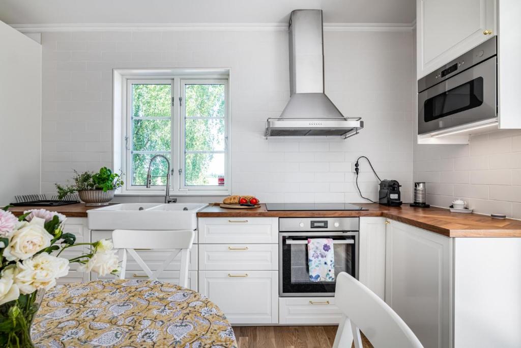 uma cozinha com armários brancos, um lavatório e uma mesa em Gård med egen sjö med bryggbåt, nyrenoverat! em Katrineholm