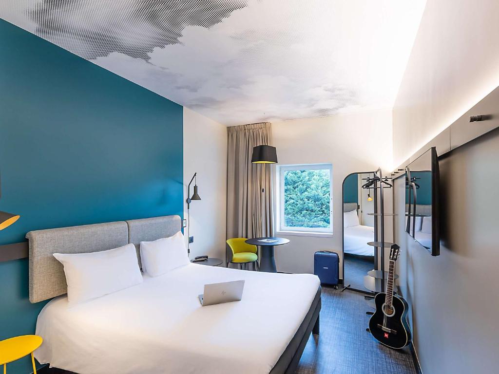 a hotel room with a white bed and a blue wall at Hotel ibis Lisboa Alfragide in Lisbon