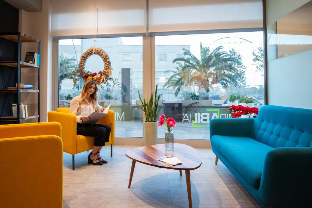 eine Frau auf einem Stuhl im Wohnzimmer in der Unterkunft Hotel Dimorae Rooms and Suites - Apartments in Civitanova Marche
