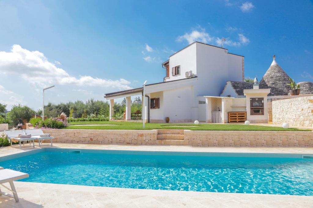 a villa with a swimming pool in front of a house at Trulli Dimore - Saveni in Castellana Grotte