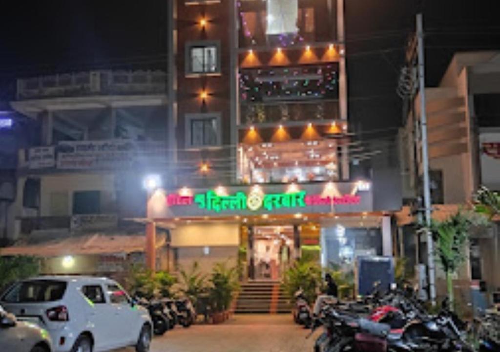 un restaurante con coches aparcados delante de él por la noche en Hotel New Delhi darbar family restaurant Jalgaon, en Jālgaon