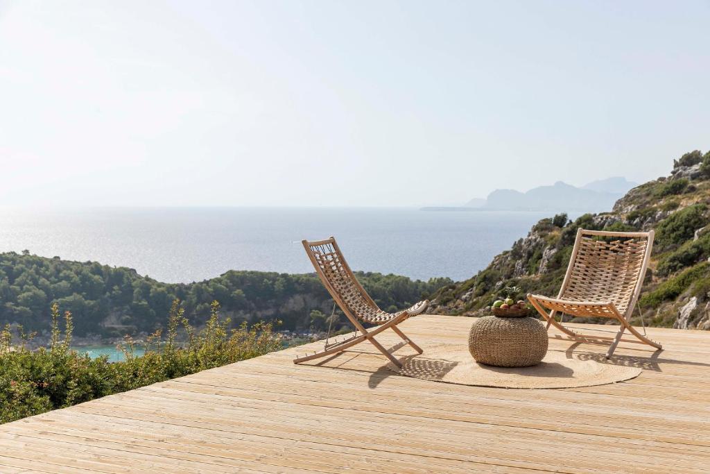 zwei Stühle und eine Vase auf einem Holzdeck in der Unterkunft Pristine Seaview Villa , with 5-Star Resort Access in Faliraki