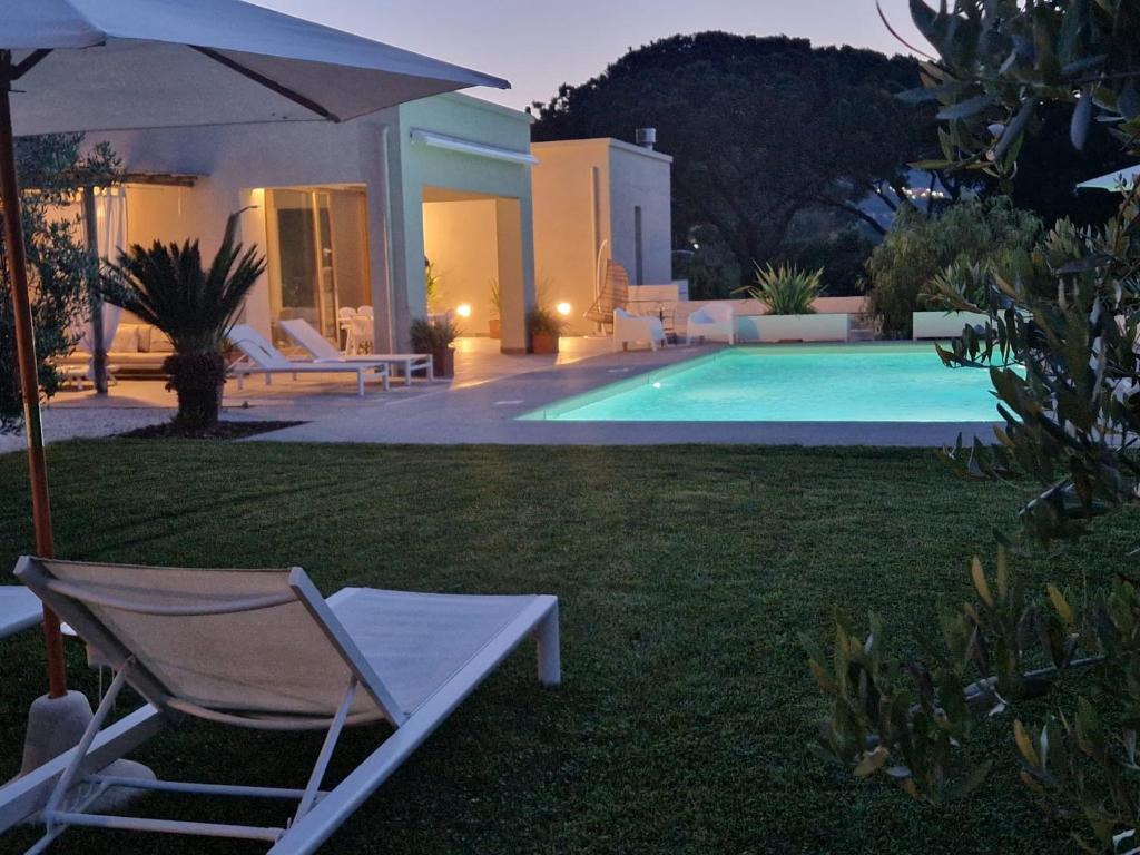 una sedia e un ombrellone accanto alla piscina di La Suite con Piscina Privata a Portoferraio