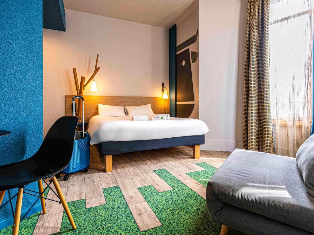 a hotel room with a bed and a couch at ibis Styles Moulins Centre in Moulins
