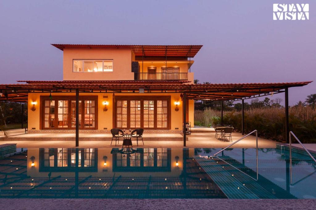 a house with a pool in front of it at Golden Sunsets by StayVista - Refreshing pool, serene lawn - your tranquil retreat in Alibaug