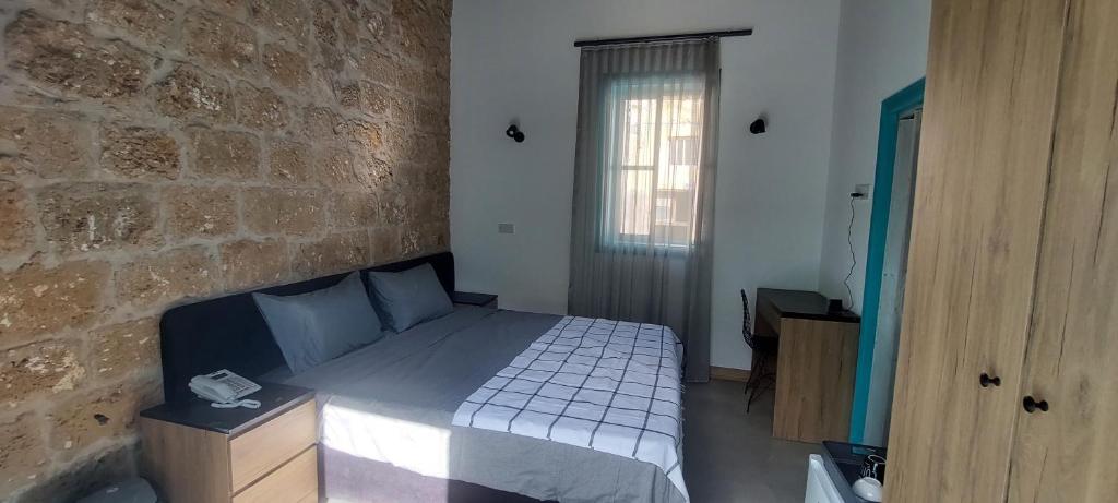 a bedroom with a bed and a brick wall at Bella Casetta Guest House in Famagusta