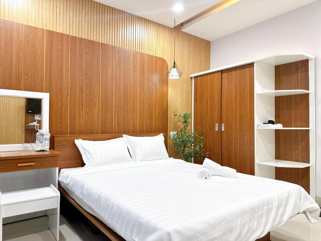 Schlafzimmer mit einem großen weißen Bett und Holzwänden in der Unterkunft Milanesa Hotel and Apartment in Vũng Tàu