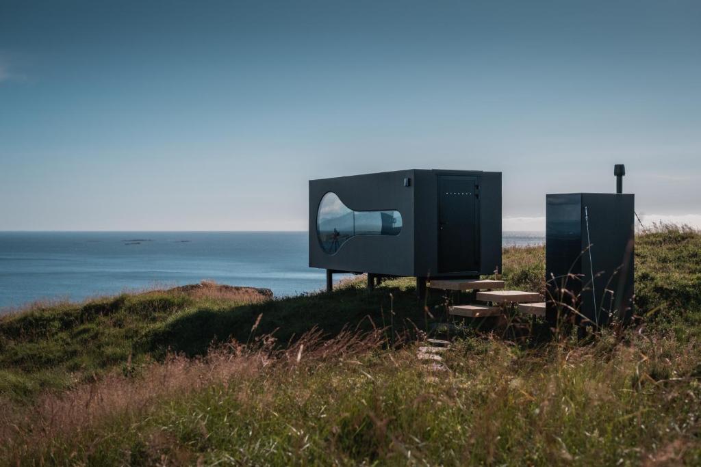 duży telewizor siedzący na szczycie wzgórza obok oceanu w obiekcie Birdbox Reksta w mieście Florø