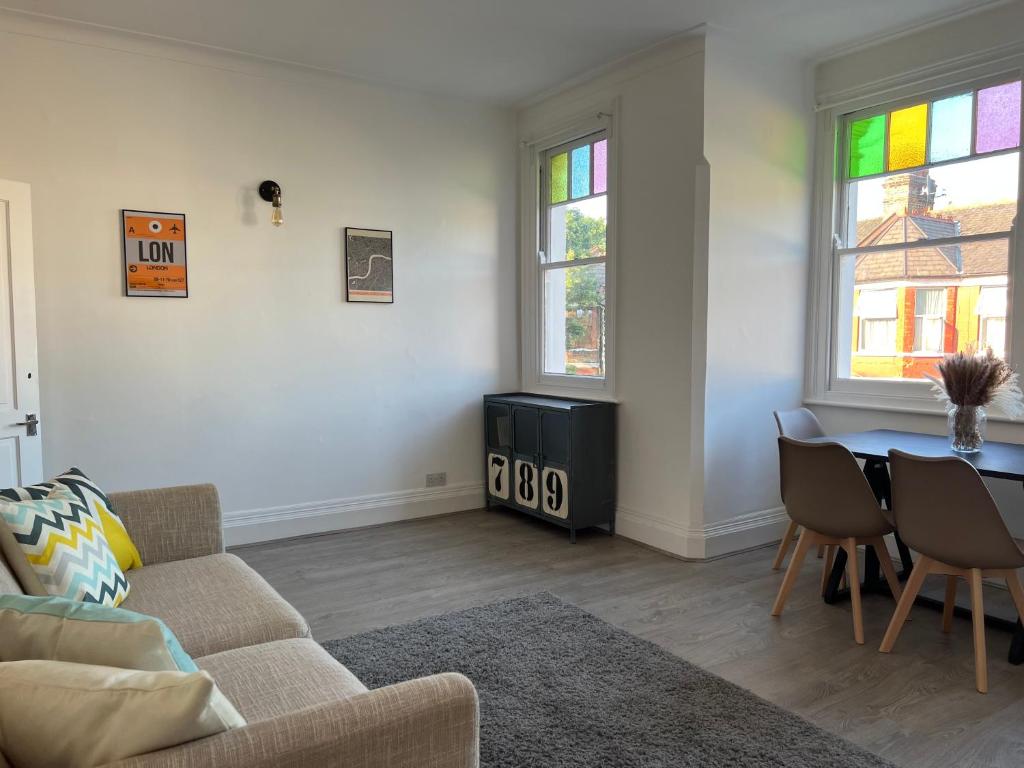 a living room with a couch and a table at Bright and Stylish 2 Bedroom First Floor Flat in London