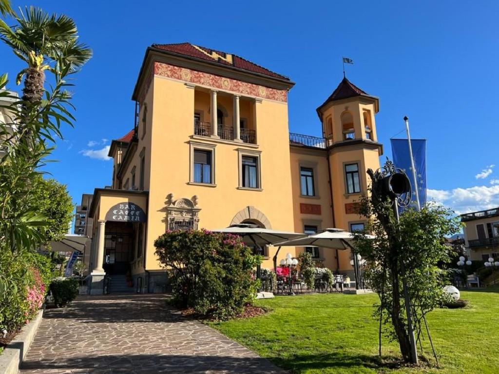 a large yellow building with a clock tower at Camin Hotel Luino in Luino