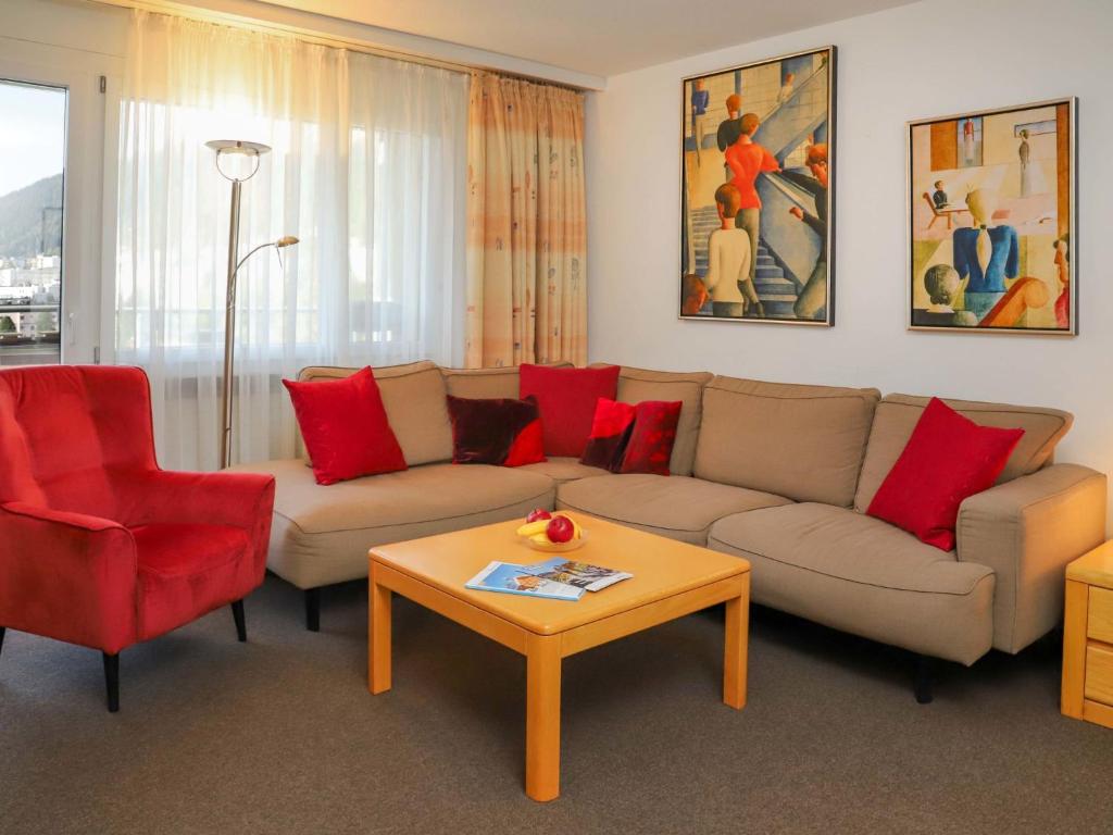 een woonkamer met een bank en rode stoelen bij Apartment Allod-Park-50 by Interhome in Davos