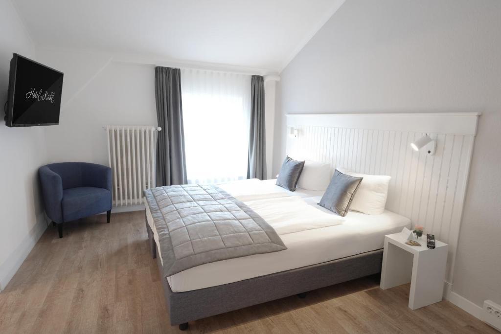 1 dormitorio con 1 cama y 1 silla azul en Hotel Kühl en Neumünster