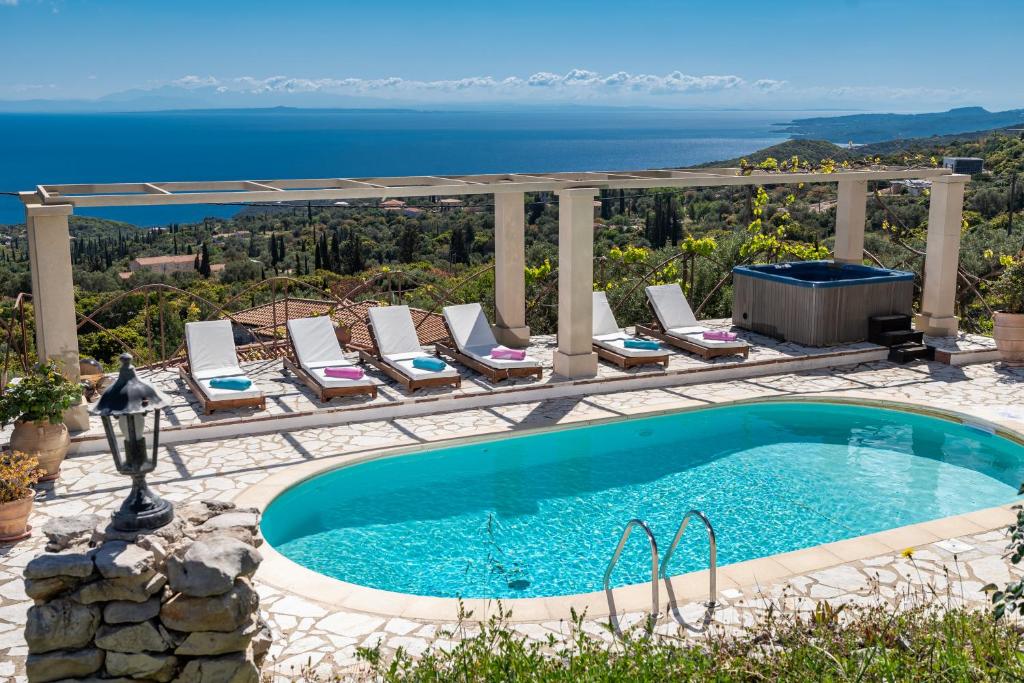 a swimming pool with lounge chairs and the ocean in the background at Villa Armos in Skinária