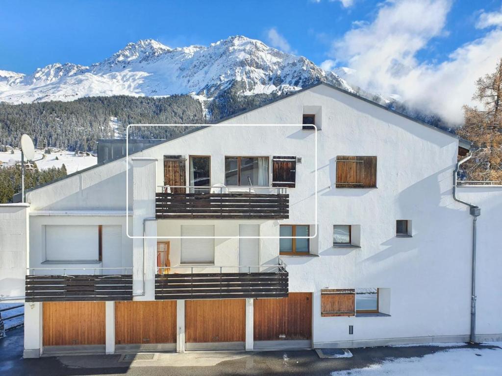 a white building with a snow covered mountain in the background at Apartment Casa Fadail Seura 21 by Interhome in Lenzerheide