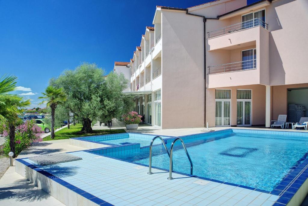 a swimming pool in front of a building at Hotel Duje in Vodice