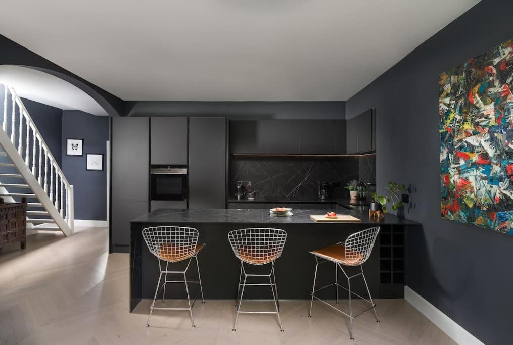 a kitchen with a island with three bar stools at The Kensington Penthouse Suite in London