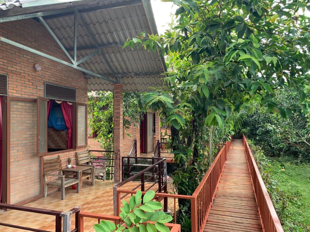 a patio with a wooden walkway to a house at Gibbon Singing Home Stay in Quan Tom