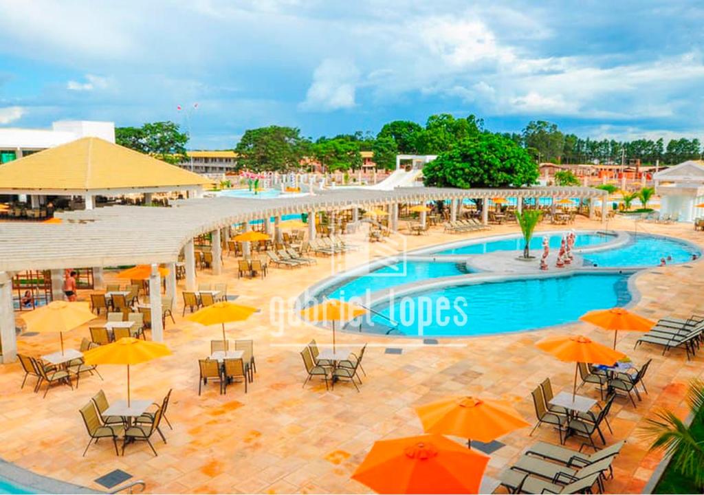 una piscina con mesas, sillas y sombrillas en L'acqua diRoma com Super Ofertas, en Caldas Novas