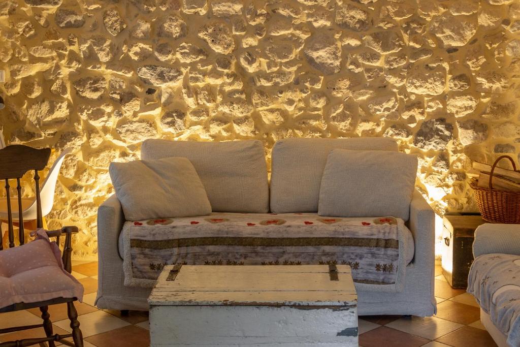 Sofá blanco en una habitación con pared en Valdastico Casetta in sasso con giardino, en Pedemonte